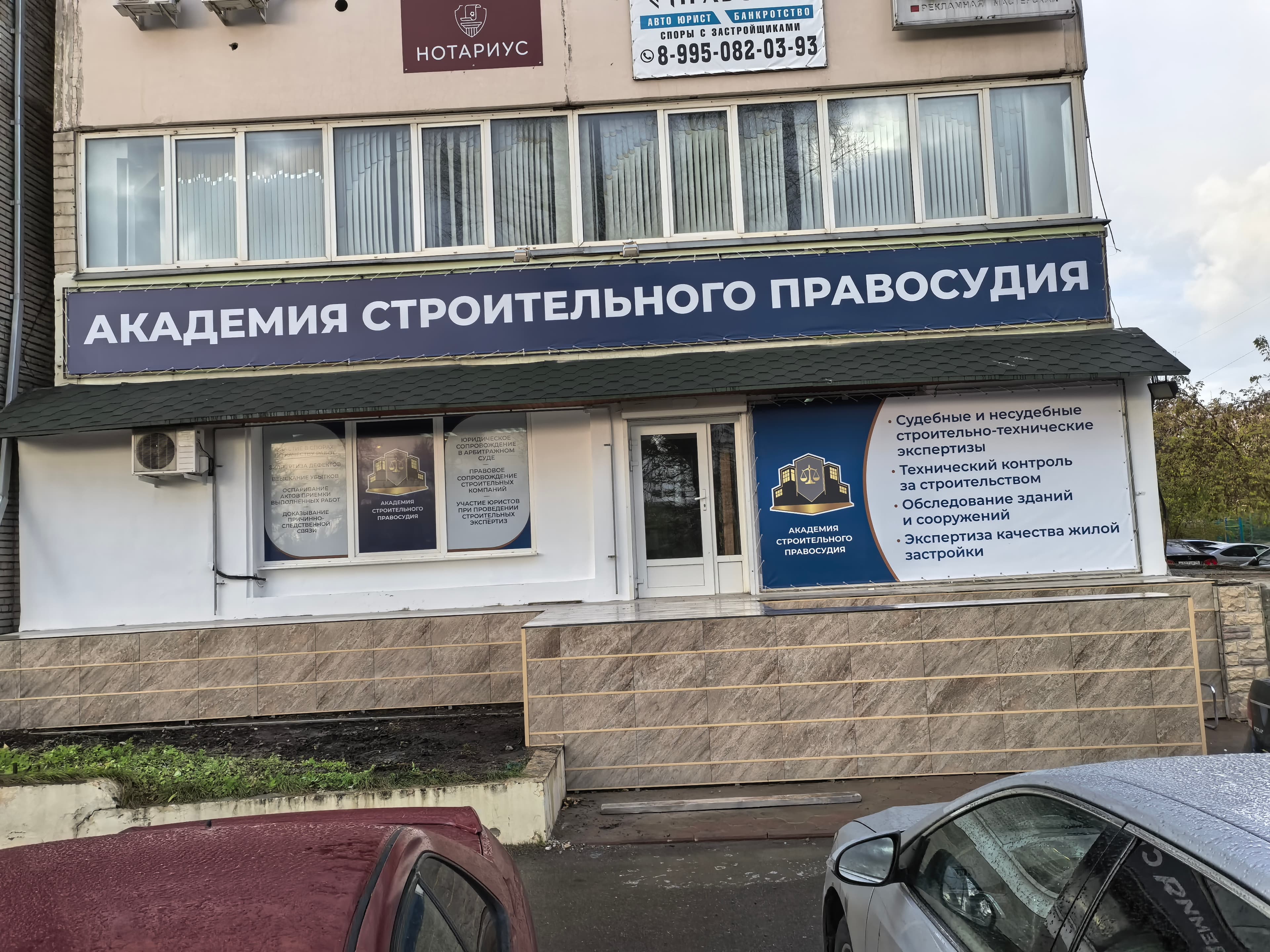Вход в офис Академии Строительного Правосудия — тёмно-синий баннер с названием компании
